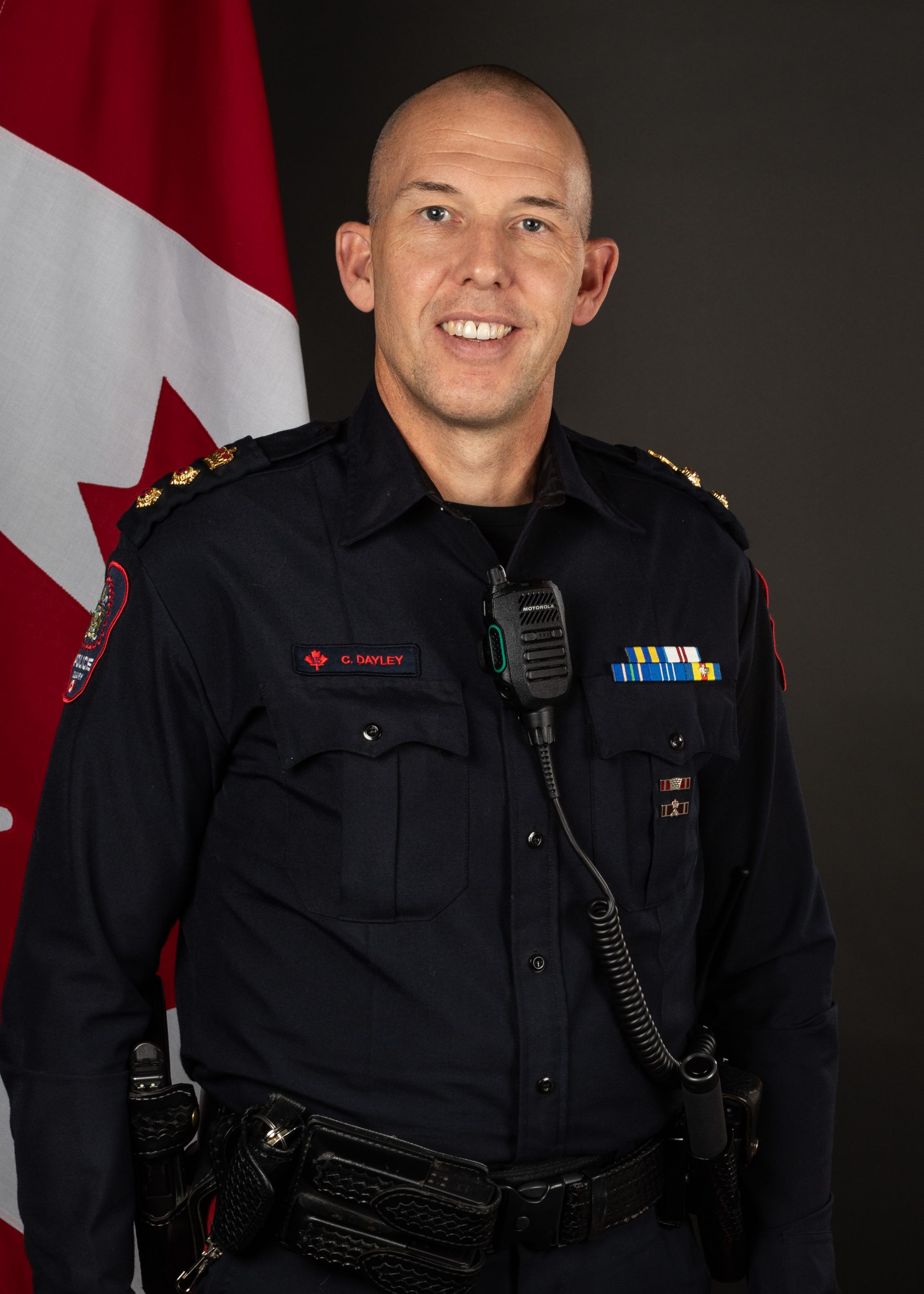 Service Portrait of Deputy Chief Cory Dayley in his uniform infront of a Canadian flag.